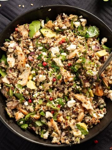 quinoa and salmon salad topped with avocado and feta in a bowl.