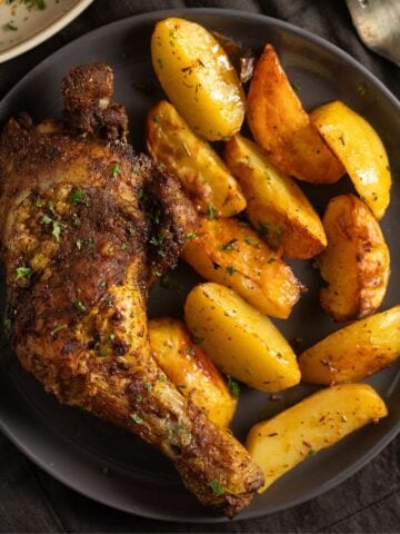 air fryer chicken quarters served with potato wedges.