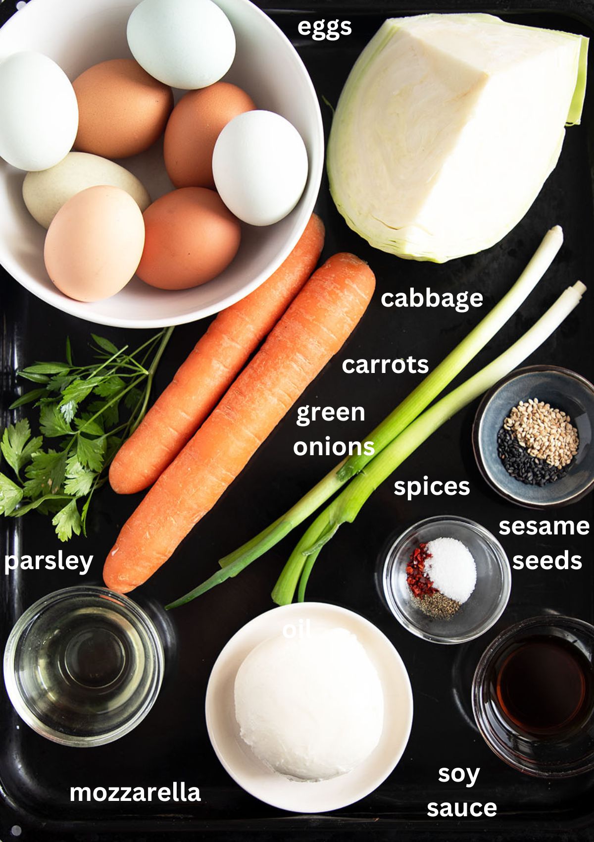 labeled ingredients for making cabbage omelet with eggs, carrots, mozzarella, and green onions.