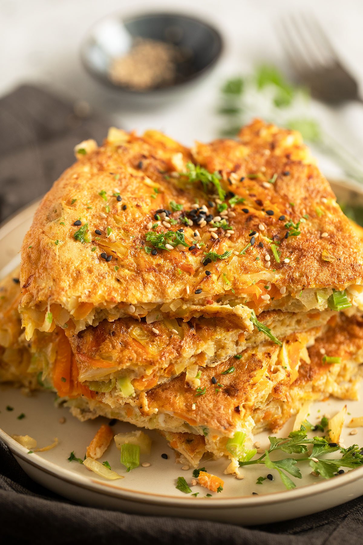 cabbage omelette with carrots, green onions, and sesame seeds sliced on a plate.