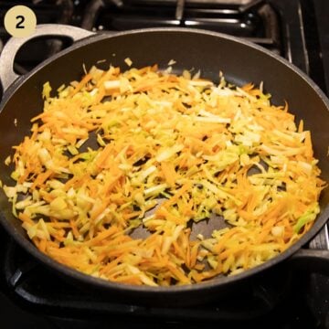 sauteing carrots and copped cabbage in a large pan.