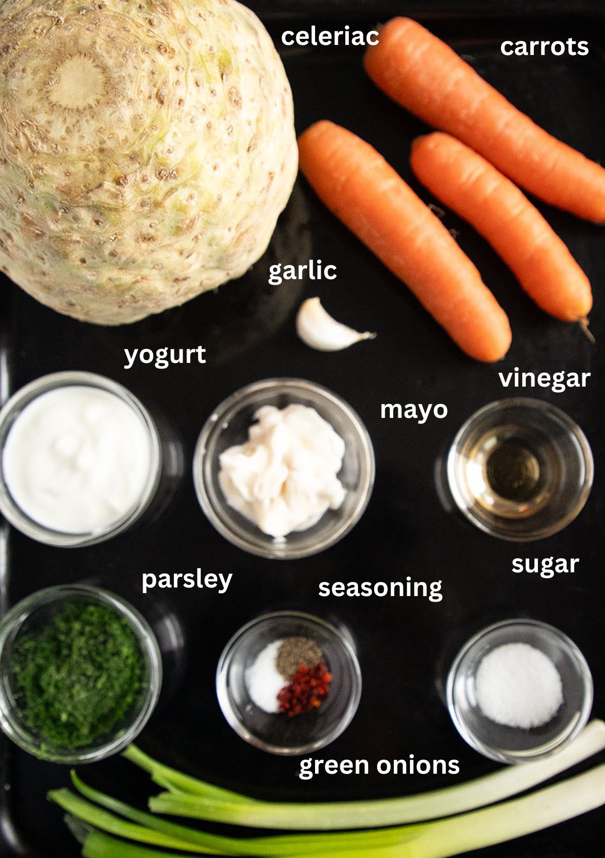 labeled ingredients for making slaw with celeriac, carrots, green onions, yogurt and mayo.