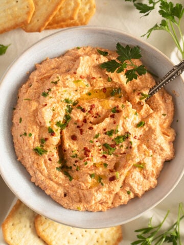 red pepper and feta dip sprinkled with parsley in a small bowl.