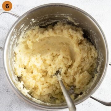stirring mashed potatoes with a spoon in a pot.