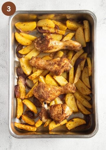 unbaked chicken legs, potatoes and onions in a roasting tin.