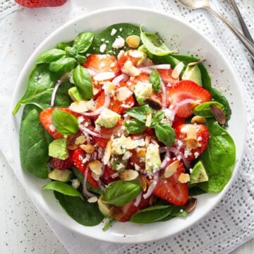 a plate with strawberry goat cheese salad on the table.