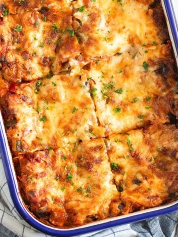 vegetable lasagna with bechamel sauce in a baking dish with blue rim.