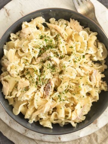 pasta with smoked trout in a large bowl on a round cutting board.