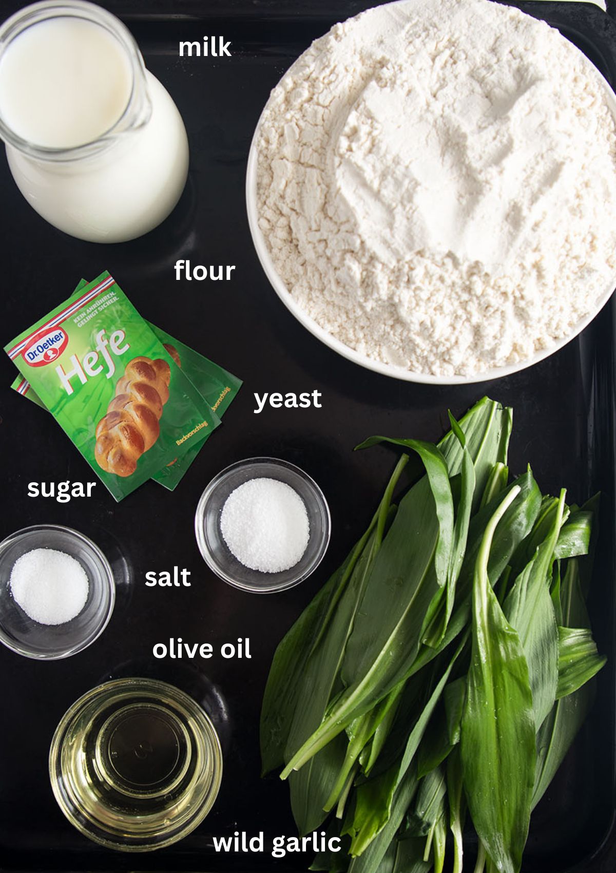 listed ingredients for making bread with wild garlic, flour, yeast, salt, milk, sugar and oil.