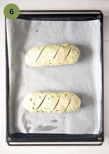 two small loaves of bread on the baking sheet before rising.
