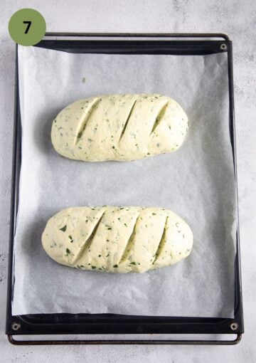two small loaves of bread on a baking sheet before baking.