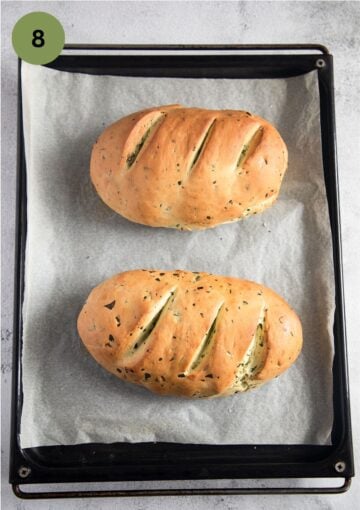 two small loaves of bread on a baking sheet lined with parchment paper.