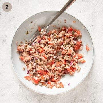 mixing mashed sardines with tomatoes and onions in a bowl.