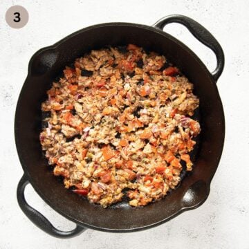 half-baked mixture of sardines, tomatoes and onions in a cast iron skillet.