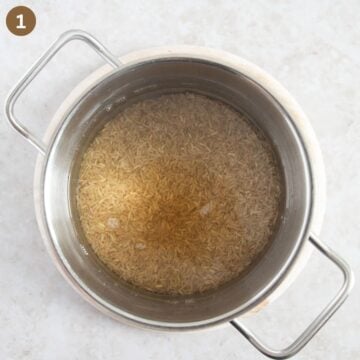 uncooked brown rice covered with water in a small pot.