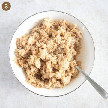 fluffing rice with a fork in a bowl.