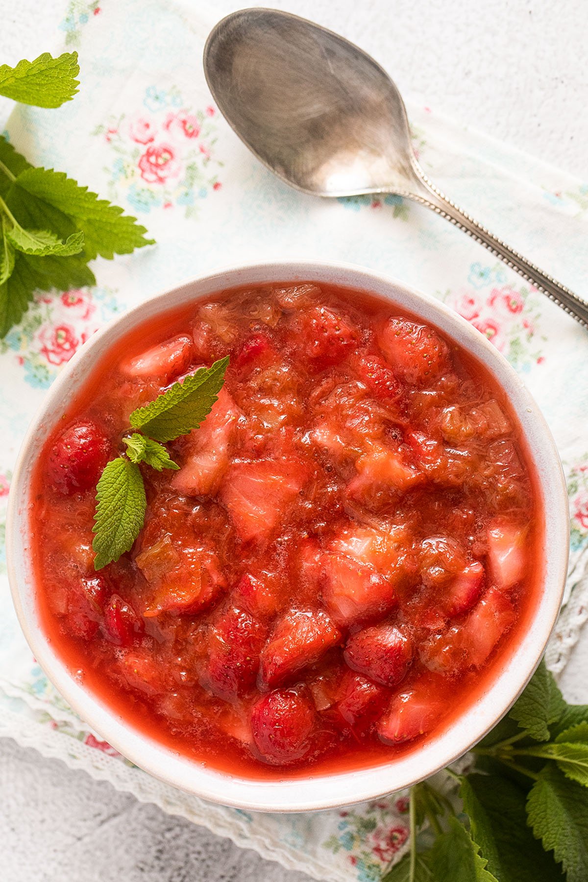bowl full of strawberry and rhubarb compote and a spoon.