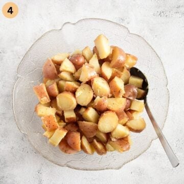 mixing cooked potatoes with salad dressing in a bowl.