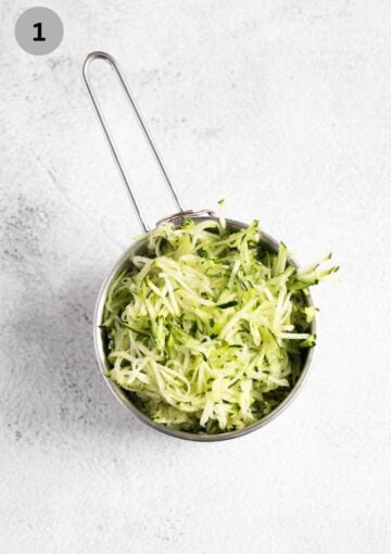 grated zucchini in a measuring cup.