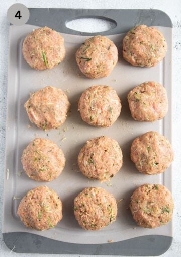 uncooked round meatballs with turkey and zucchini on a cutting board.