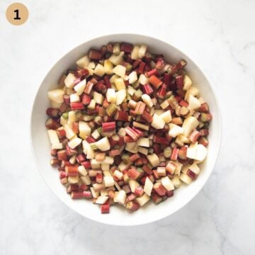 chopped apples and rhubarb mixed with sugar in a bowl.