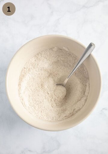 mixing dry ingredients for muffin batter in a large bowl with a spoon.