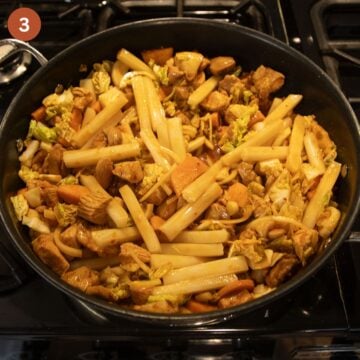 rice cakes and chicken pieces cooking in a saucepan.