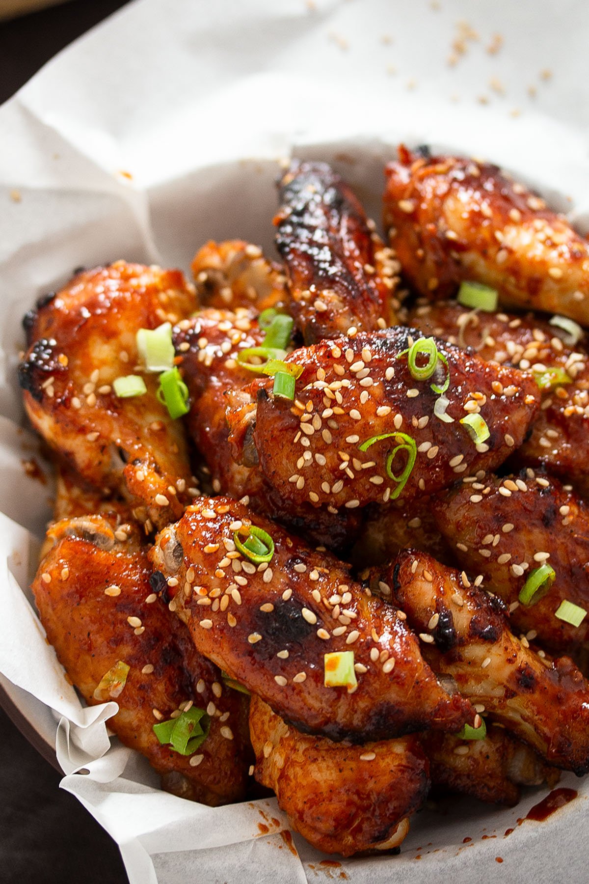 chicken wings glazed with gochujang sauce and sprinkled with green onions.