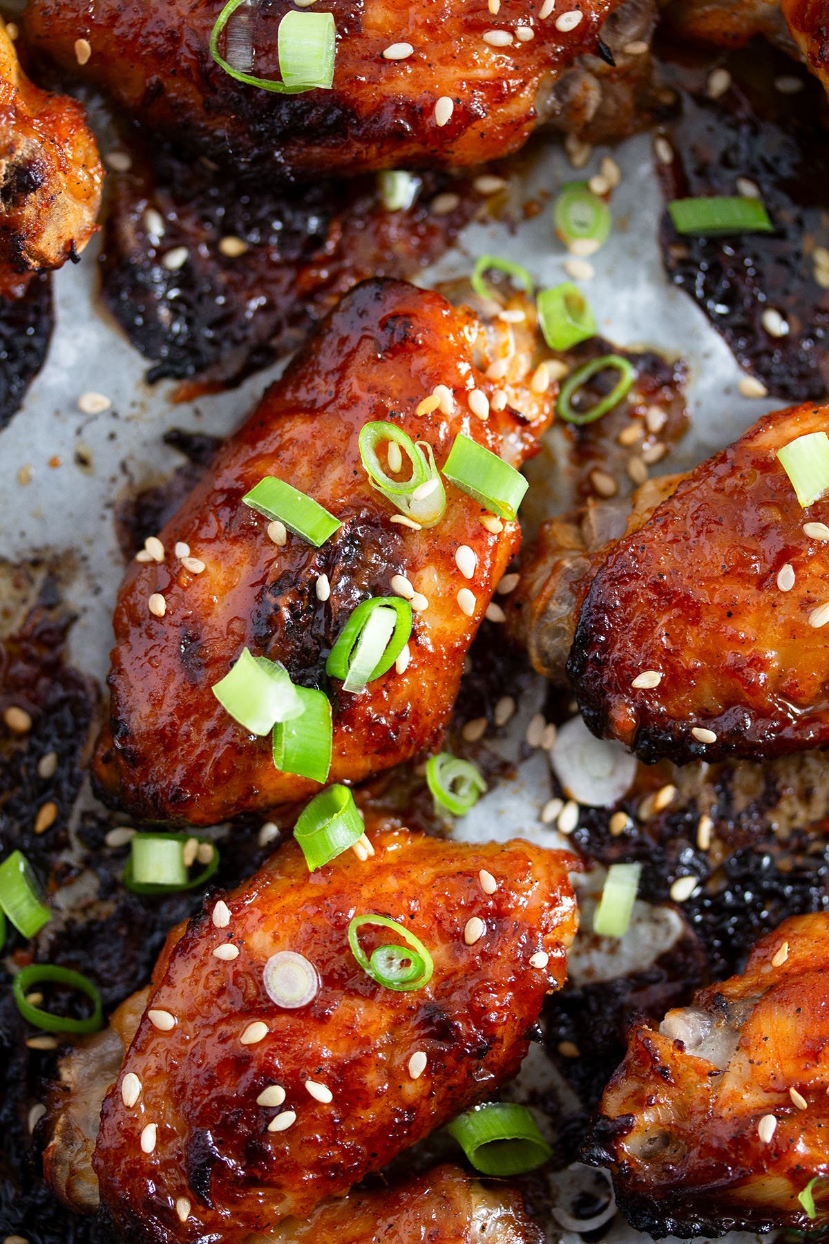 glossy gochujang chicken wings sprinkled with green onions and sesame.