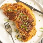 rolled zucchini omelette with fork and knife on a plate.