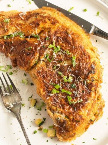 rolled zucchini omelette with fork and knife on a plate.