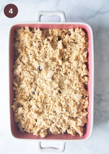 unbaked apple and cherry crumble with streusel on top in a baking dish.
