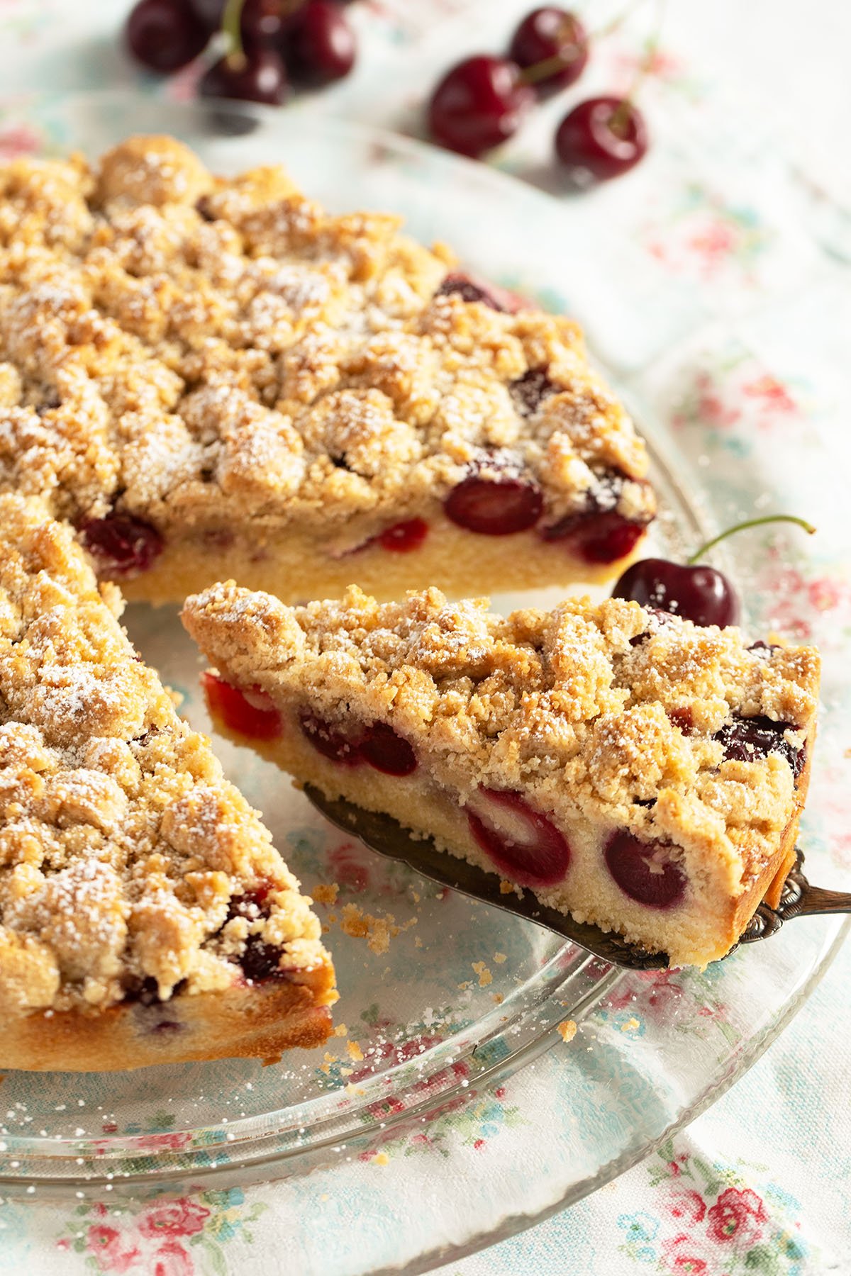 a slice cut from a cherry crumb cake showing the cherries inside.