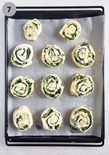 unbaked feta and spinach rolls on a baking sheet lined with parchment paper.