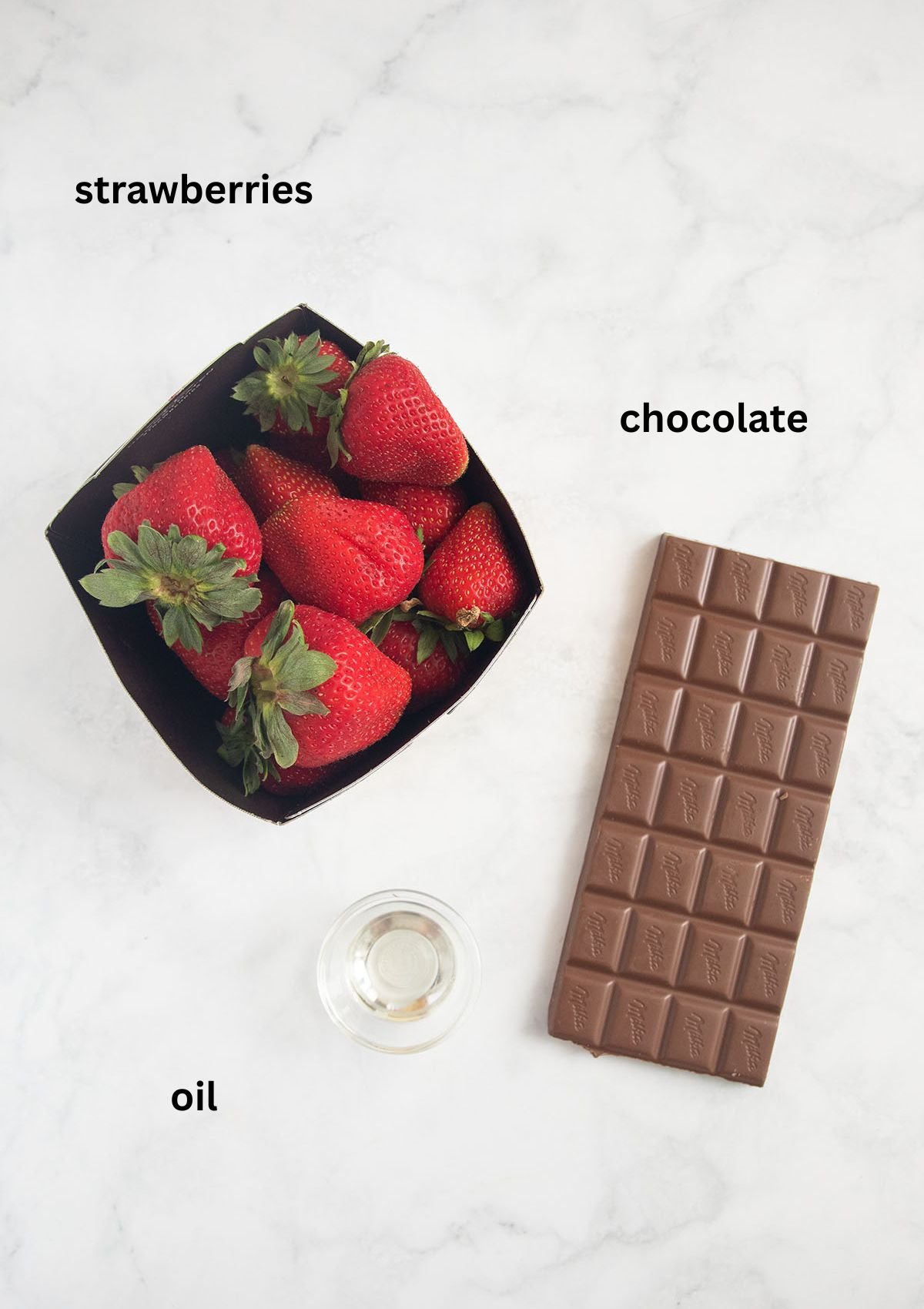 labeled ingredients: one bar of milk chocolate, fresh strawberries and a little oil in a small bowl.