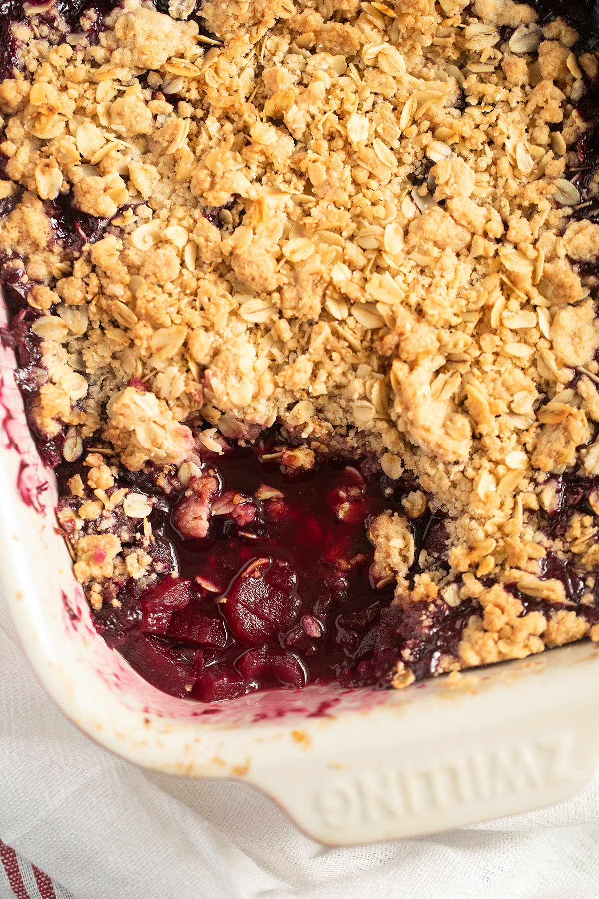 apple blueberry crumble in a baking dish showing the jammy filling underneath the golden crumble.