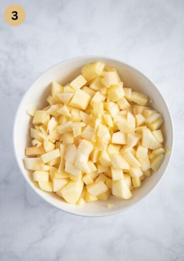 finely chopped apples mixed with lemon juice in a bowl for making crumble with blueberries.