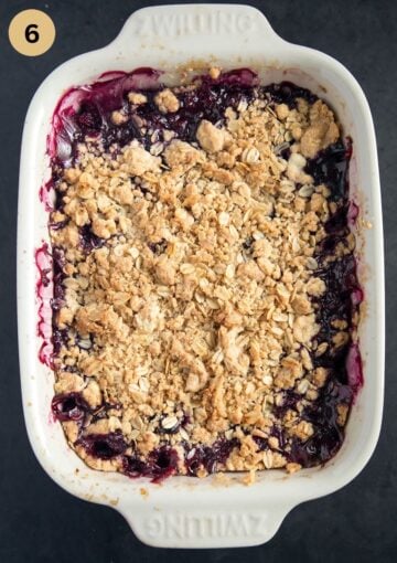 Baked apple and blueberry crumble with golden oat topping, served in a baking dish.