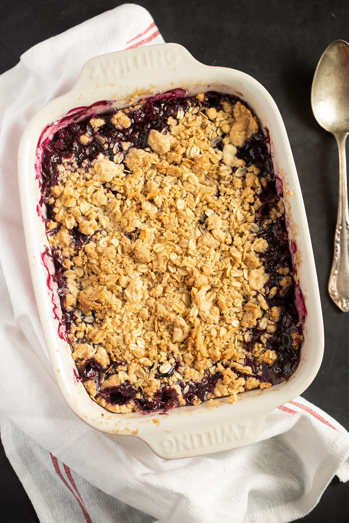 baking dish full of hot apple and blueberry crumble on a white kitchen cloth.