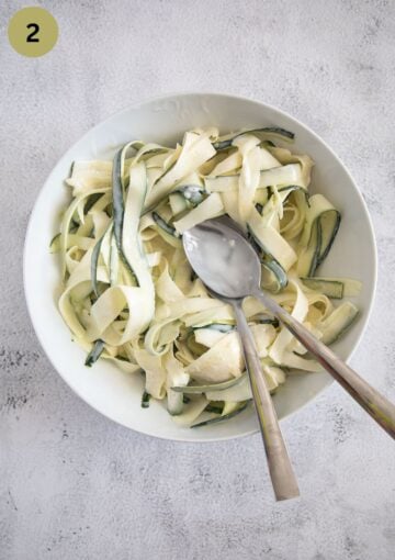 marinating zucchini strips with cream and seasoning in a a bowl.
