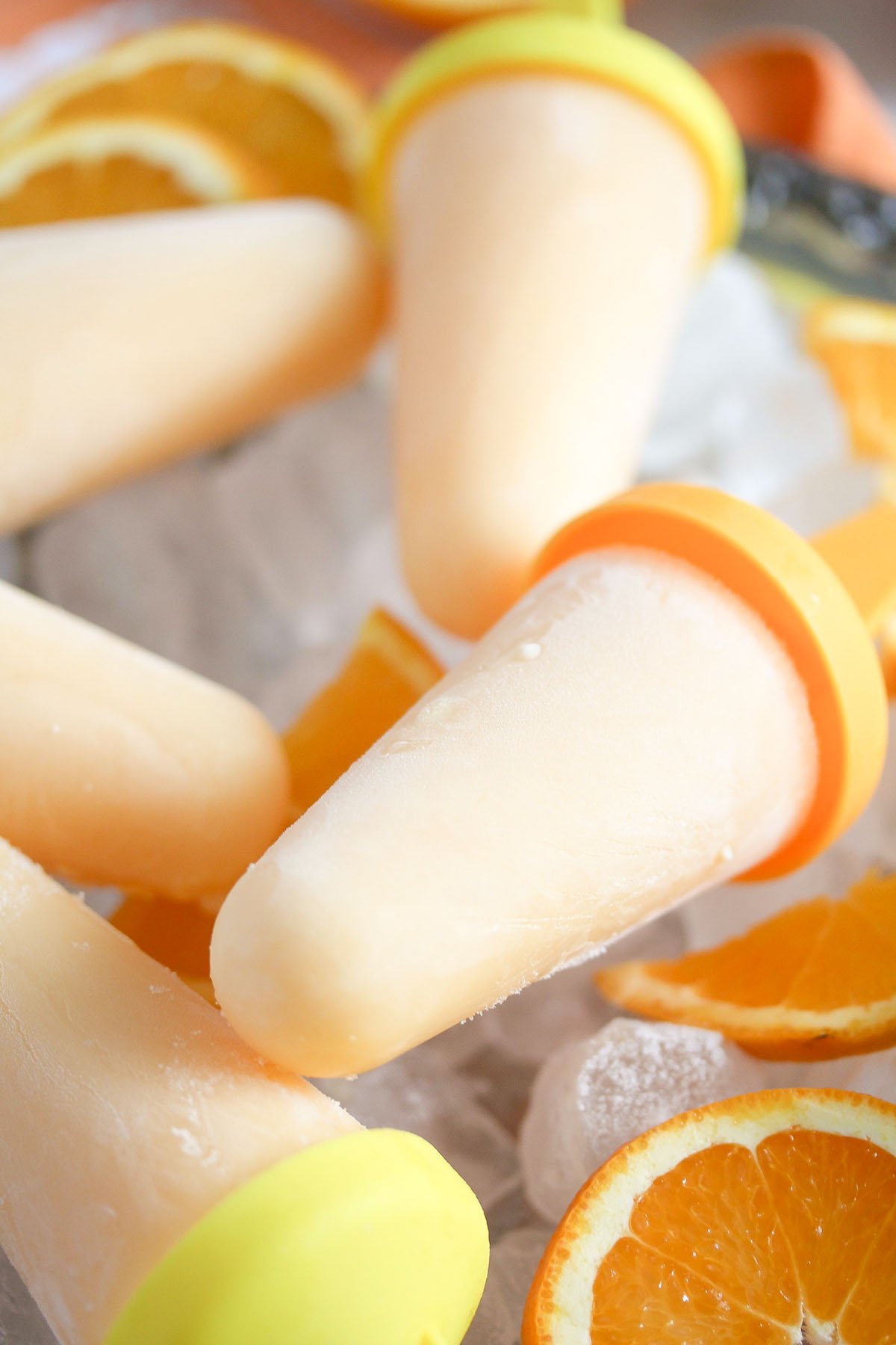 many orange popsicles crowded on ice cubes.