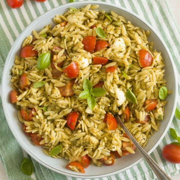 orzo pesto pasta salad with tomatoes and mozzarella in a bowl.