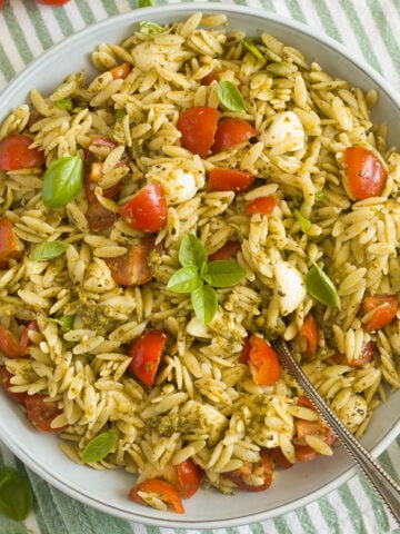 orzo pesto pasta salad with tomatoes and mozzarella in a bowl.