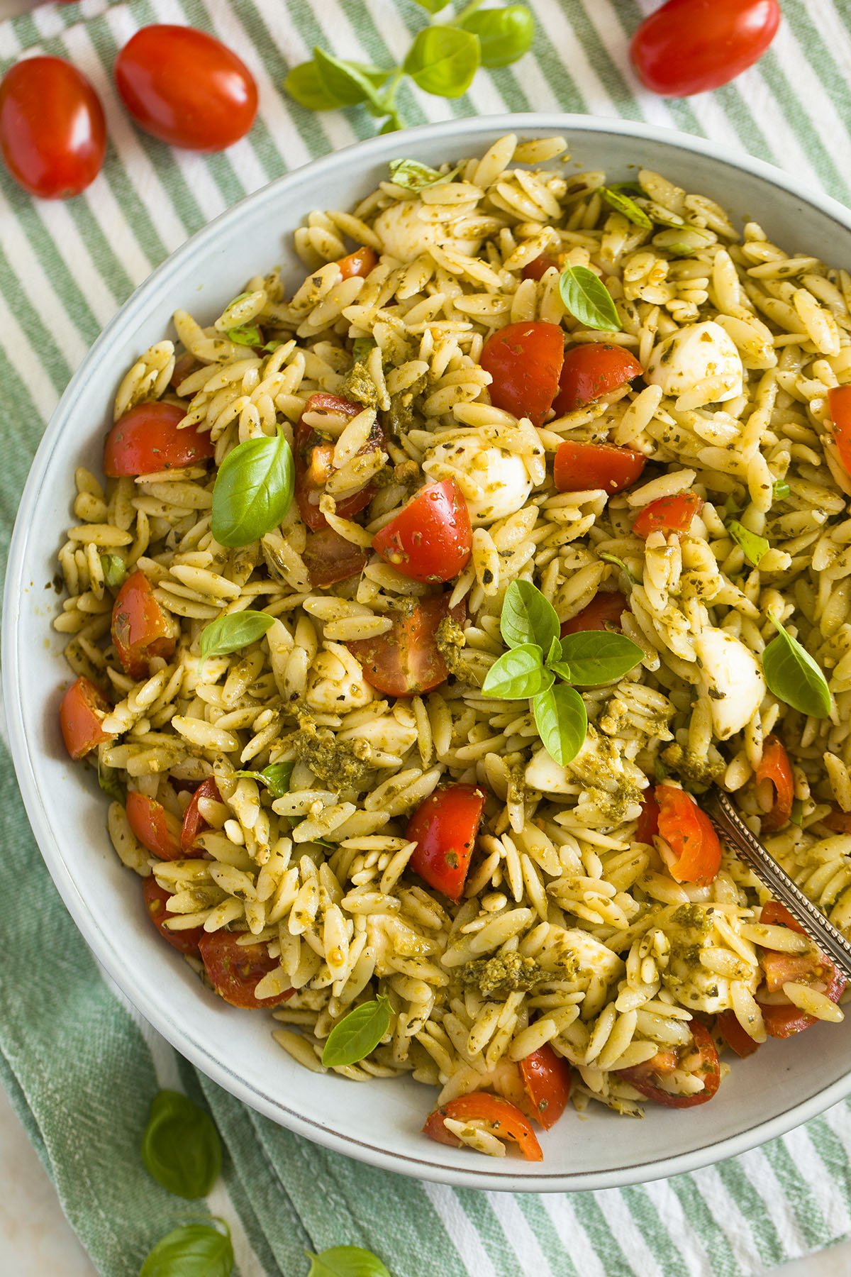 orzo pesto salad with tomatoes, mozzarella and basil in a bowl.