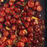 roasted tomatoes for pasta sauce cooked with onions and garlic on a baking sheet.
