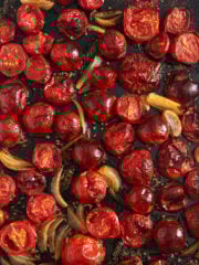 roasted tomatoes for pasta sauce cooked with onions and garlic on a baking sheet.