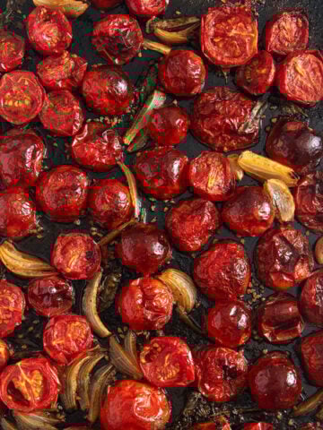 roasted tomatoes for pasta sauce cooked with onions and garlic on a baking sheet.