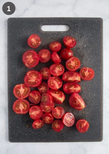 halved small tomatoes on a cutting board.