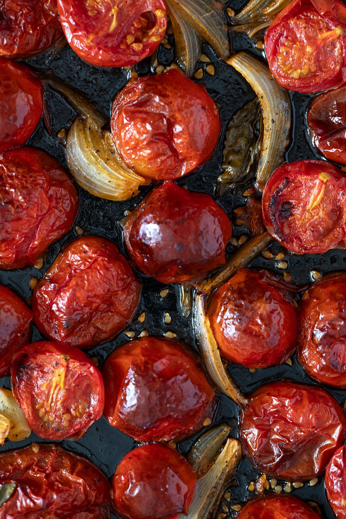roasted tomatoes, onions and garlic for making pasta sauce on a baking tray.