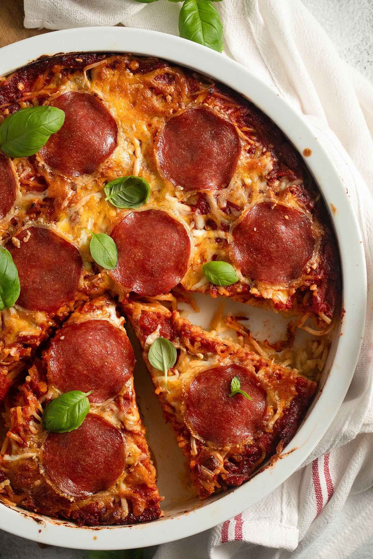 Easy spaghetti pizza recipe with crispy pasta crust, melted cheese, and savory salami.